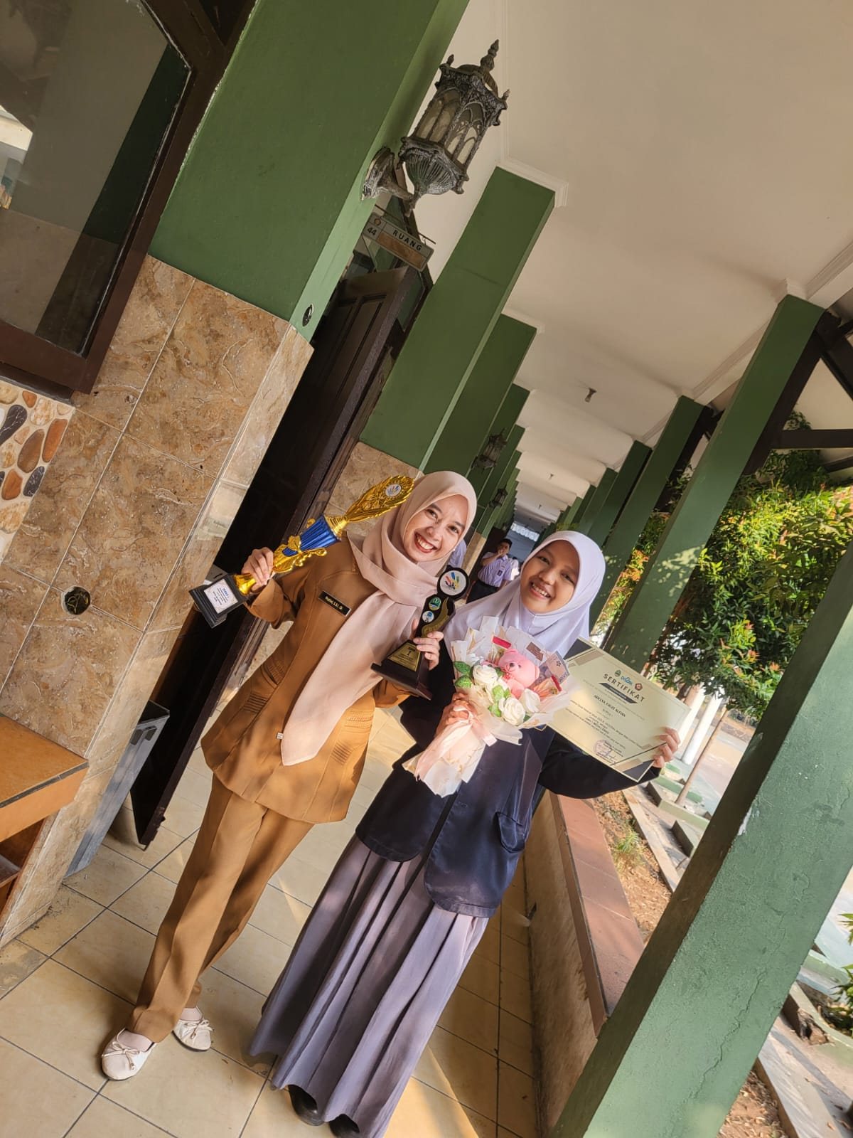 Adelya Fauzi Alfian bersama guru pembimbingnya, Ibu Pratiwi, membawa piala dan sertifikat